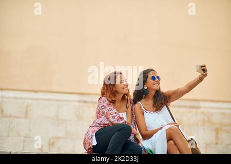 Un selfie pour tous les jours de notre voyage. Plan court de deux jeunes sœurs attrayantes prenant des selfies dans une ville étrangère. Banque D'Images