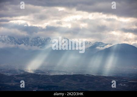 Lumière du soleil perçant à travers les nuages et frappant les montagnes Banque D'Images