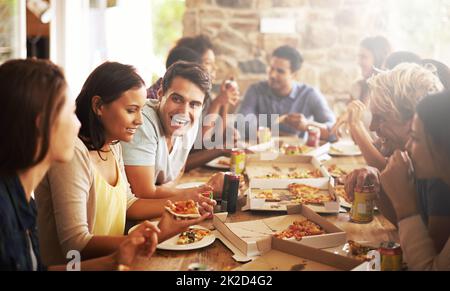 Super amis et nourriture. Photo d'un groupe d'amis en train de savourer une pizza ensemble. Banque D'Images