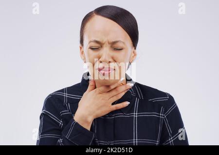 J'ai besoin d'y aller bientôt. Photo en studio d'une jeune femme souffrant d'un mal de gorge sur fond gris. Banque D'Images