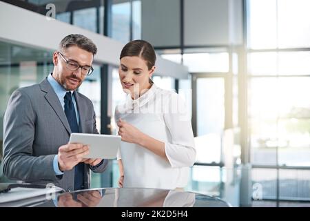 Shes un collègue de confiance. Photo rognée de deux hommes d'affaires regardant une tablette numérique au bureau. Banque D'Images