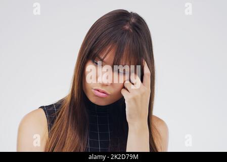 Parfois c'est difficile à décider. Photo studio d'une jeune femme qui a l'air réfléchie sur un fond gris. Banque D'Images