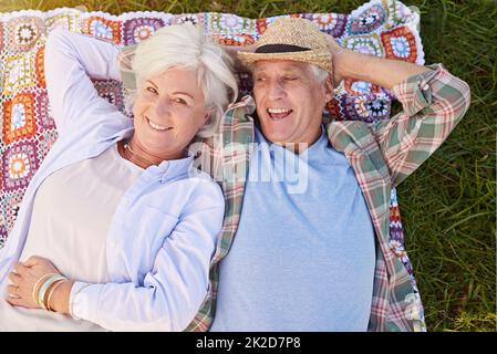 C'est une retraite reposante. Portrait d'un heureux couple senior qui se détend ensemble sur la pelouse. Banque D'Images