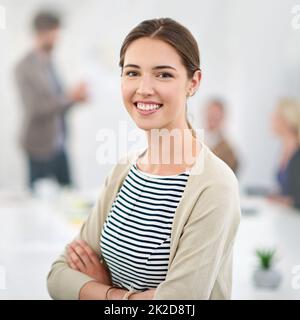 C'est là que le succès se produit. Portrait d'une jeune femme d'affaires dans un bureau avec des collègues en arrière-plan. Banque D'Images