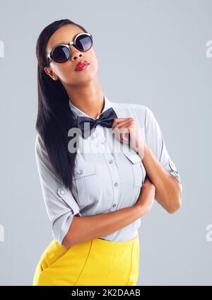 Shes got her own style. Cropped portrait of a trendy young woman wearing shades against a gray background. Stock Photo