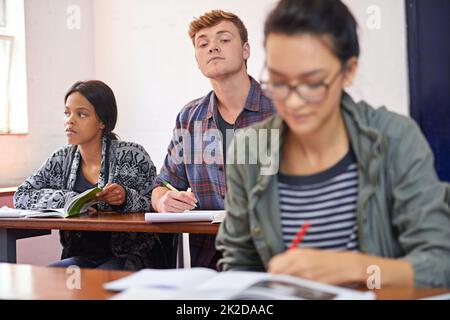 Cheaters are only cheating themselves. a student trying to see another students work in class. Stock Photo