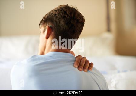 Cibler la douleur. Vue arrière d'un jeune homme souffrant d'une douleur au cou. Banque D'Images