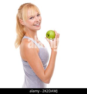 Tout ce que je mange est bon pour moi. Portrait studio d'une jolie femme blonde tenant une pomme. Banque D'Images