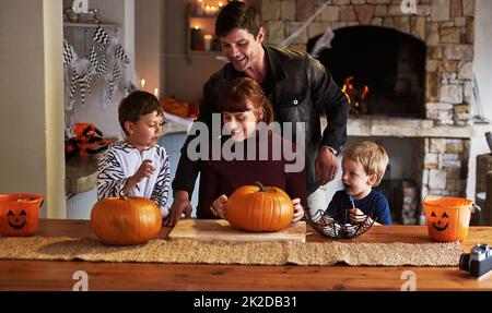 Il est temps de passer un bon moment. Photo d'une adorable jeune famille qui sculptera des citrouilles et fêtera halloween ensemble à la maison. Banque D'Images