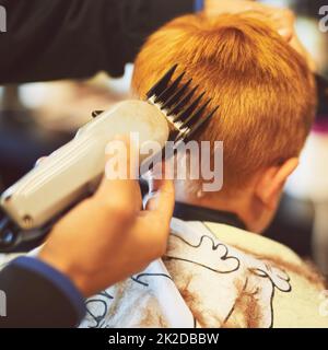 Il est temps de changer de look. Gros plan d'un jeune garçon qui obtient une coupe de cheveux dans un salon de coiffure. Banque D'Images