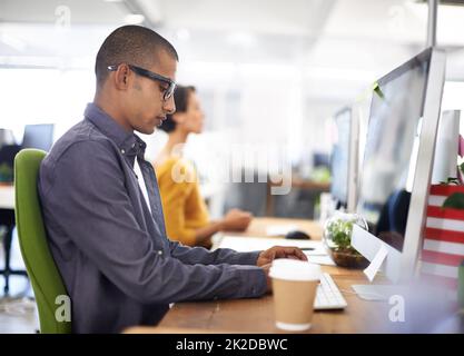 Se concentrer sur son travail. Un jeune designer travaillant au bureau. Banque D'Images