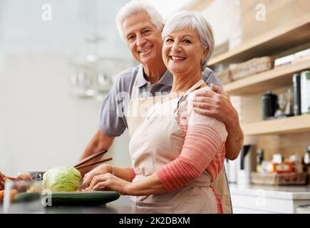 Nous étions vieux ensemble mais notre amour reste nouveau. Photo d'un mari et d'une femme heureux dans leur cuisine. Banque D'Images