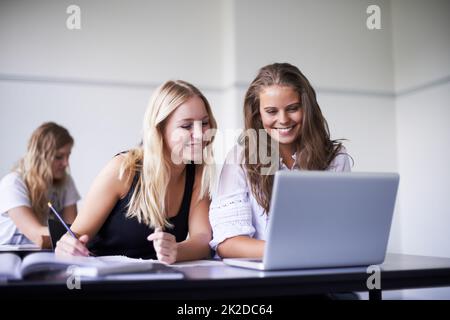 Apprendre de nouvelles choses chaque jour. Deux filles adolescentes qui travaillent sur un ordinateur portable en classe. Banque D'Images
