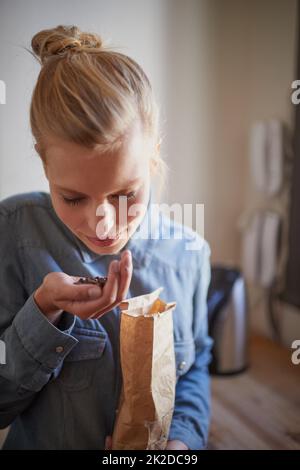 Arôme frais de grains de café. Une jeune femme sentant des grains de café frais dans sa cuisine. Banque D'Images