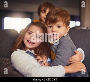 C'est le plus mignon. Portrait court d'une adorable petite fille et de ses deux frères dans leur salon à la maison. Banque D'Images