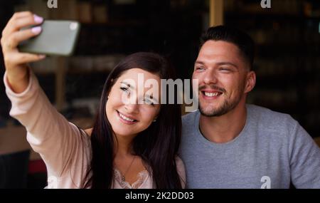 Le temps de selfie avec ma personne préférée. Photo courte d'un jeune couple qui prend un selfie tout en étant assis ensemble. Banque D'Images