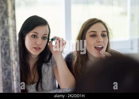 Juste un couple de cascades. Photo courte de deux jeunes amies mettant du maquillage dans la salle de bains. Banque D'Images