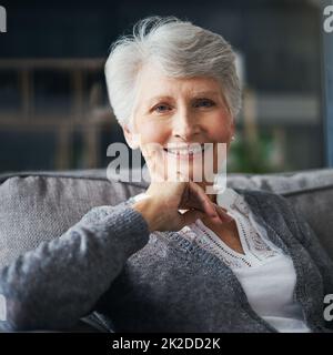 C'est là que la messagerie instantanée est la plus heureuse. Portrait d'une femme âgée qui se détend sur le canapé à la maison. Banque D'Images