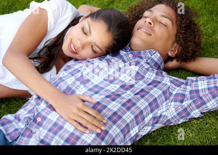 Après-midi paresseux ensemble. Photo d'un jeune couple heureux qui se nouent sur la pelouse. Banque D'Images