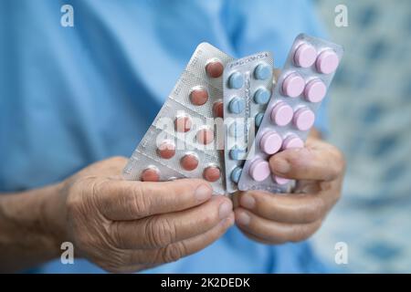 Asian senior elderly old lady woman holding pills drug in her hand, healthy strong medical concept. Stock Photo