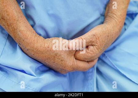 Asiatique aînée femme patiente a mis la main sur elle.Lap seul pour attendre sa famille. Banque D'Images