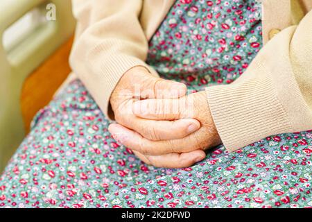 Asiatique aînée femme patiente a mis la main sur elle.Lap seul pour attendre sa famille. Banque D'Images