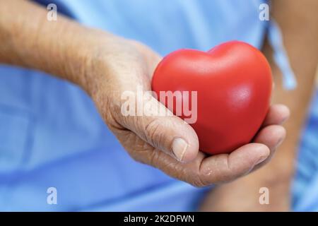 .Asiatique aînée femme patiente tenant cœur rouge à l'hôpital. Banque D'Images