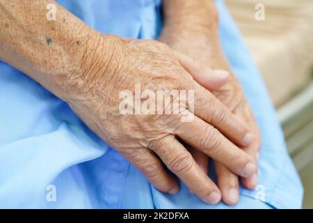 Asiatique aînée femme patiente a mis la main sur elle.Lap seul pour attendre sa famille. Banque D'Images