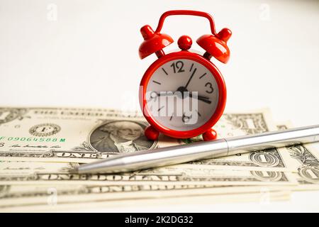 Alarm clock with coins on US dollar banknotes, finance installment loan time. Stock Photo