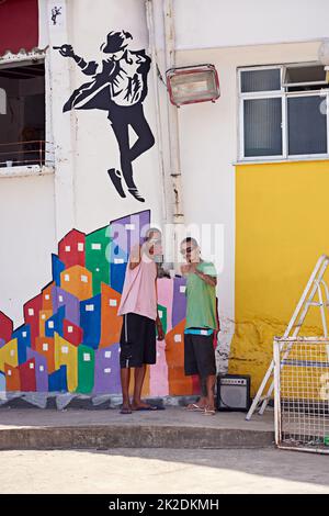 Owning the city. two young graffiti artists standing by their wall art. Stock Photo