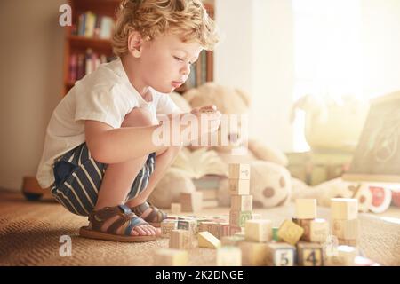 Construire son imagination, construire son esprit. Photo d'un adorable petit garçon jouant avec des blocs de bois à la maison. Banque D'Images