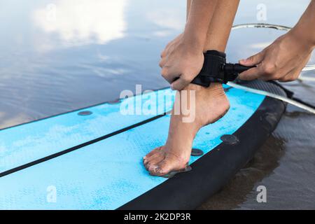 Une femme attache la laisse de surf sur sa cheville Banque D'Images