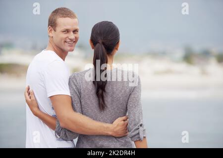 Tout ce qui compte, c'est que ça soit heureux. Photo d'un jeune couple regardant la vue sur la plage. Banque D'Images