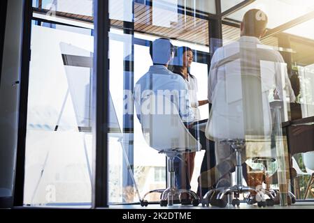 Penseurs en action dans la salle de conférence. Photo d'un groupe de jeunes femmes présentant un tableau blanc à leurs collègues dans une salle de réunion. Banque D'Images