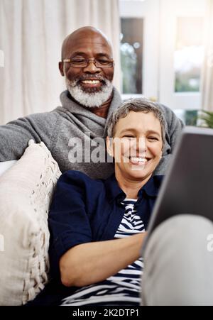 Nous avons passé un merveilleux week-end à l'intérieur. Prise de vue d'un couple aîné affectueux utilisant une tablette tout en se relaxant sur le canapé à la maison. Banque D'Images