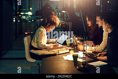 Cette équipe met dans tout le travail. Prise de vue rognée de jeunes employés travaillant tard dans la soirée. Banque D'Images