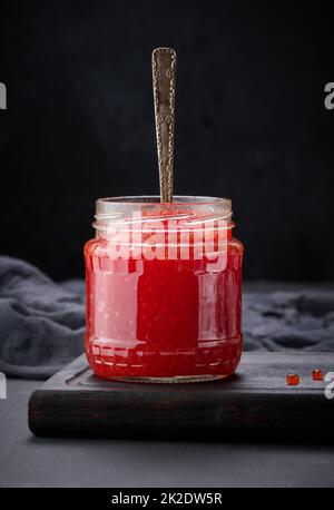 caviar rouge granuleux frais dans un pot en verre sur une table en bois Banque D'Images