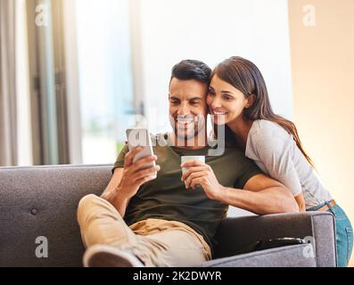 Venez pour un selfie, babe. Photo d'un jeune couple qui prend des selfies ensemble à la maison. Banque D'Images