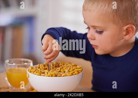 Qui a besoin d'une cuillère. Photo d'un jeune garçon prenant le petit déjeuner à la maison. Banque D'Images