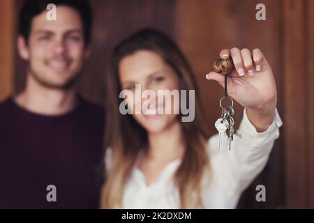 Les clés de notre maison douce maison. Portrait d'un jeune couple tenant les clés de leur nouvelle maison. Banque D'Images