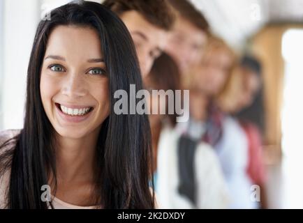 Elle aime la vie universitaire. Portrait d'un beau jeune étudiant debout avec ses amis. Banque D'Images