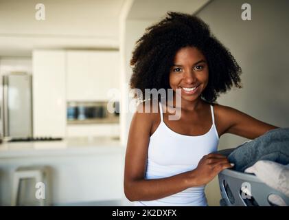 Il est temps de faire mes tâches quotidiennes. Photo courte d'une jeune femme attrayante faisant le linge à la maison. Banque D'Images