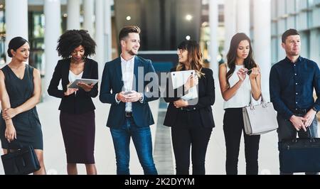 Qu'attendons-nous ? Photo d'un groupe de jeunes gens d'affaires confiants debout dans une rangée à côté l'un de l'autre à l'intérieur du bureau pendant la journée. Banque D'Images