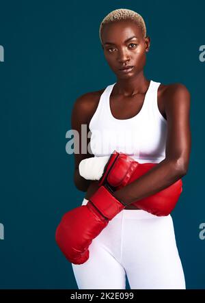 Repoussez vos limites. Portrait court d'un joli boxeur féminin debout avec ses gants de boxe sur fond sombre. Banque D'Images