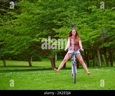 Divertissement en roue libre. Photo d'une jeune femme en vélo dans le parc. Banque D'Images