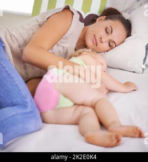 Shes toujours près de son bébé. Une jeune mère couchée à côté de son bébé endormi sur le lit. Banque D'Images