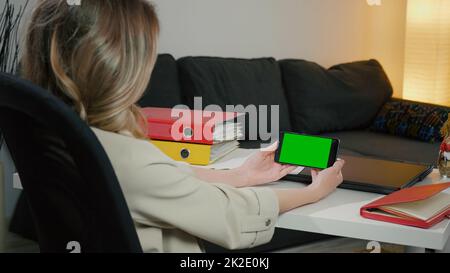 Vue arrière de la femme au téléphone avec écran vert pour l'espace de copie. Une femme d'affaires de bureau à domicile a un appel vidéo important. Banque D'Images