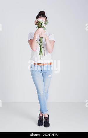 Votre confiance en vous. Photo de studio d'une femme méconnaissable portant un bouquet de fleurs sur fond gris. Banque D'Images