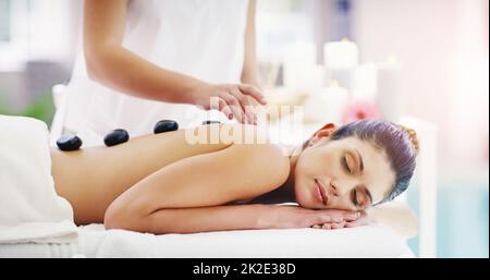 C'est un endroit pour rétablir l'équilibre. Photo d'une jeune femme recevant un massage aux pierres chaudes dans un spa. Banque D'Images