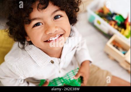 Le temps de jeu est mon moment préféré de la journée. Portrait d'un adorable petit garçon assis sur le sol et jouant avec ses jouets à la maison. Banque D'Images